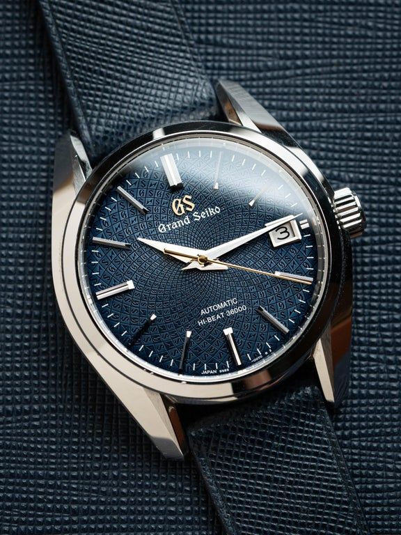 Close-up of a Grand Seiko SBGH267 Whirlpool watch featuring an intricate dark blue mosaic dial with geometric GS pattern, silver Zaratsu-polished hands, and a gold seconds hand.